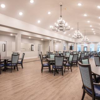 A spacious dining room with elegant chandeliers and neatly arranged tables and chairs.