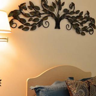 A cozy bedroom interior featuring metal wall art above the headboard, complemented by a soft lamp and decorative pillows.