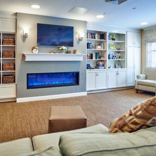 A cozy living room featuring a modern electric fireplace and built-in bookshelves.