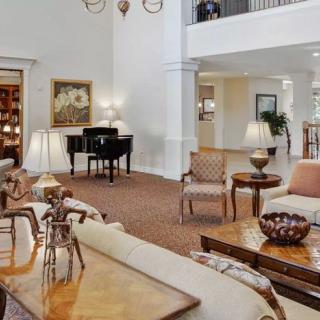 A spacious and elegant living area featuring a grand piano, stylish furniture, and tasteful artwork.