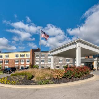 A modern building with an American flag flying in front under a clear blue sky.