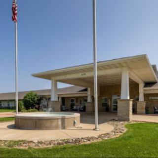 A welcoming entrance to a building featuring a fountain and flag.