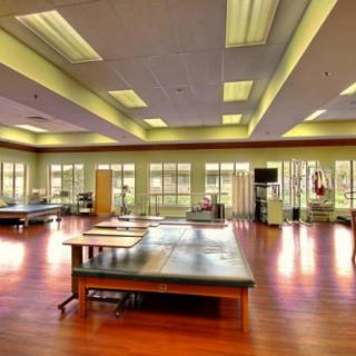 A spacious therapy room with exercise equipment and treatment tables in a healthcare facility.