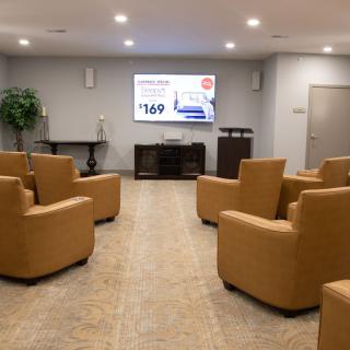 A modern waiting room with comfortable seating and a television screen.