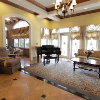 A luxurious living room featuring a grand piano, elegant furniture, and large windows.