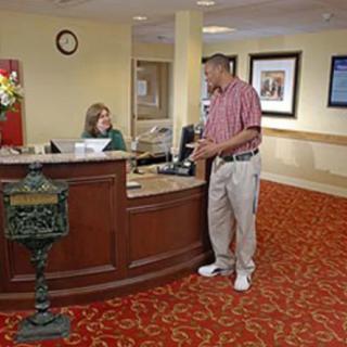 A man interacting with the receptionist at a hotel lobby desk.