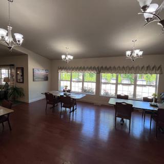 A spacious and well-lit dining area featuring tables and chairs, complemented by natural light from the large windows.