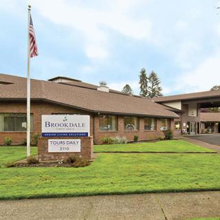 A healthcare facility with a sign and an American flag on the lawn.