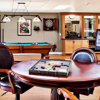 A well-furnished game room featuring a pool table, dartboard, and backgammon set.