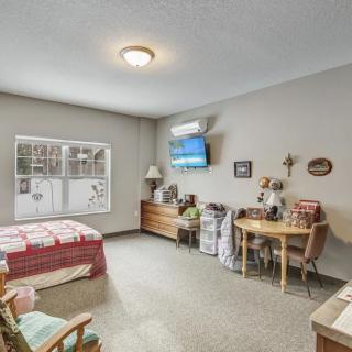 A cozy bedroom featuring a bed, desk with chair, and a wall-mounted television.