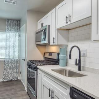 A modern kitchen featuring white cabinets and stainless steel appliances.