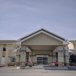 A modern building entrance with large windows and a sloped roof under a clear sky.