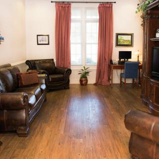 A cozy living room with leather sofas, a television, and a small desk with a computer.