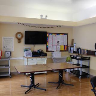 A well-lit meeting room with a large table, television, and storage units.