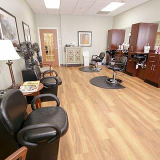 A well-organized hair salon interior with chairs, mirrors, and wooden flooring.