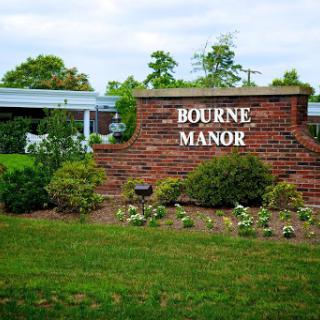 Welcome sign for Bourne Manor surrounded by lush greenery.