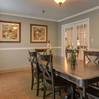 A cozy dining room with a large table and chairs, adorned with artwork and warm lighting.
