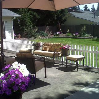 A sunny backyard patio with comfortable seating and colorful flowers.