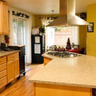 A spacious kitchen with a central countertop, stove, and bright cabinetry.