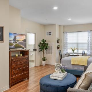 A cozy studio apartment with a comfortable seating area, TV, and elegant furnishings.