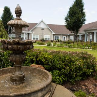 A serene garden with a decorative fountain in front of residential buildings.