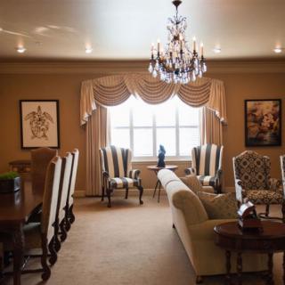 A traditional living and dining area featuring a chandelier, elegant furniture, and framed artwork.