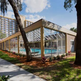 A modern building with a glass-enclosed swimming pool surrounded by trees.