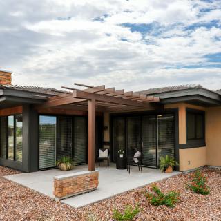 A modern house with a patio and outdoor seating under a cloudy sky.