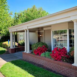 A charming house with a covered porch, blooming flowers, and well-maintained garden.