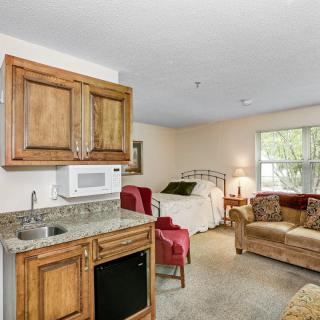 A cozy studio apartment with a kitchenette, bed, and small living area.