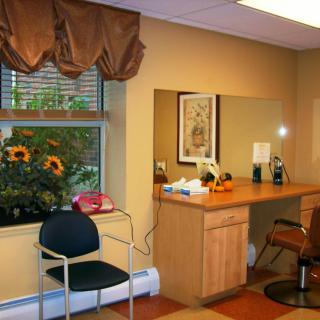 A cozy office space with a desk, chairs, and a window adorned with plants.
