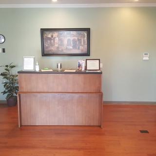 A well-organized reception area with a wooden desk, wall art, and a potted plant.