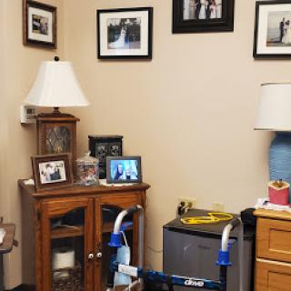 A cozy corner of a room featuring a wooden side table, decorative lamp, and framed photos.