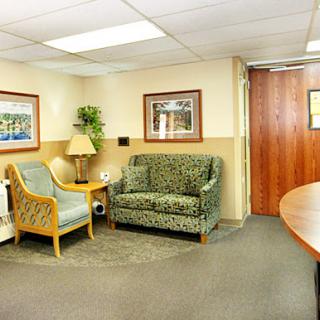 A cozy waiting area featuring a sofa and chairs, adorned with artwork and indoor plants.