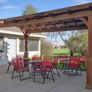 A cozy outdoor patio with red chairs and a pergola, perfect for relaxing in the garden.