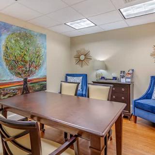 A well-decorated office meeting room featuring a large table, chairs, and colorful artwork on the wall.