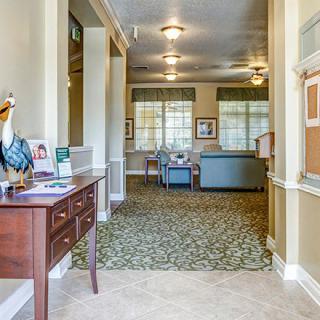 A well-lit hallway with decorative furnishings and carpeted flooring leading to a seating area.