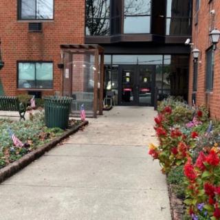 Entrance to a red brick building with colorful flowers lining the pathway.