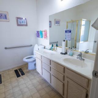 A well-lit bathroom featuring a sink, toilet, and ample storage space.