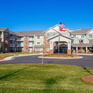 A modern residential apartment building with an entrance and flags flying outside.