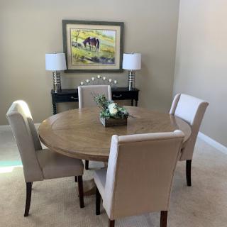 A cozy dining area featuring a round table surrounded by upholstered chairs, complemented by elegant lamps and wall art.