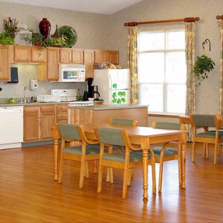 A modern kitchen and dining area featuring wooden furniture and hardwood floors, decorated with plants for a cozy atmosphere.