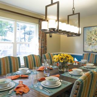 A well-decorated dining room with a table set for a meal, featuring striped chairs and a floral centerpiece.
