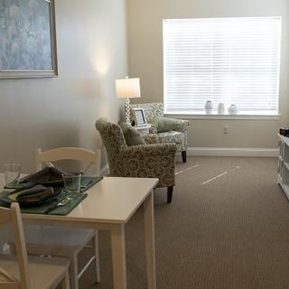 Cozy living room with armchairs, a small dining table, and a lamp by the window.