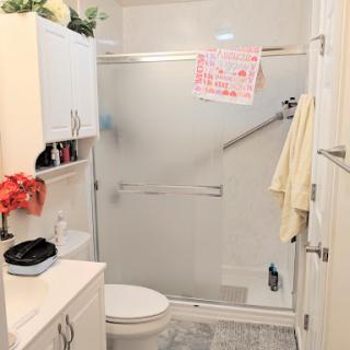 A compact and modern bathroom featuring a shower, toilet, and storage space.
