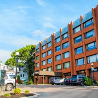 A brick hotel building with parked cars in front and a clear blue sky.