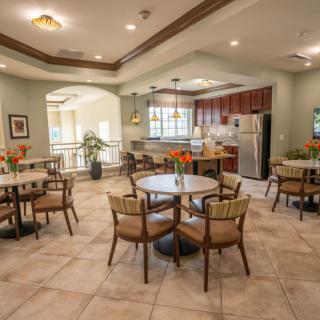 A cozy dining area with several tables and chairs, adjacent to a modern kitchen.