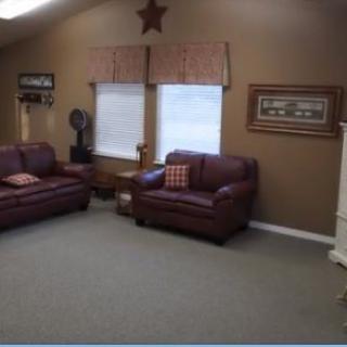 A cozy living room with leather sofas, large windows, and decorative wall elements.