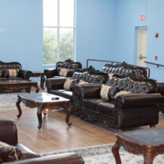 A spacious living room with elegant sofas and wooden coffee tables, set against a light blue wall.