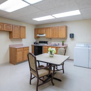 A spacious kitchen and dining area featuring wooden cabinets, a dining table with chairs, and essential appliances.